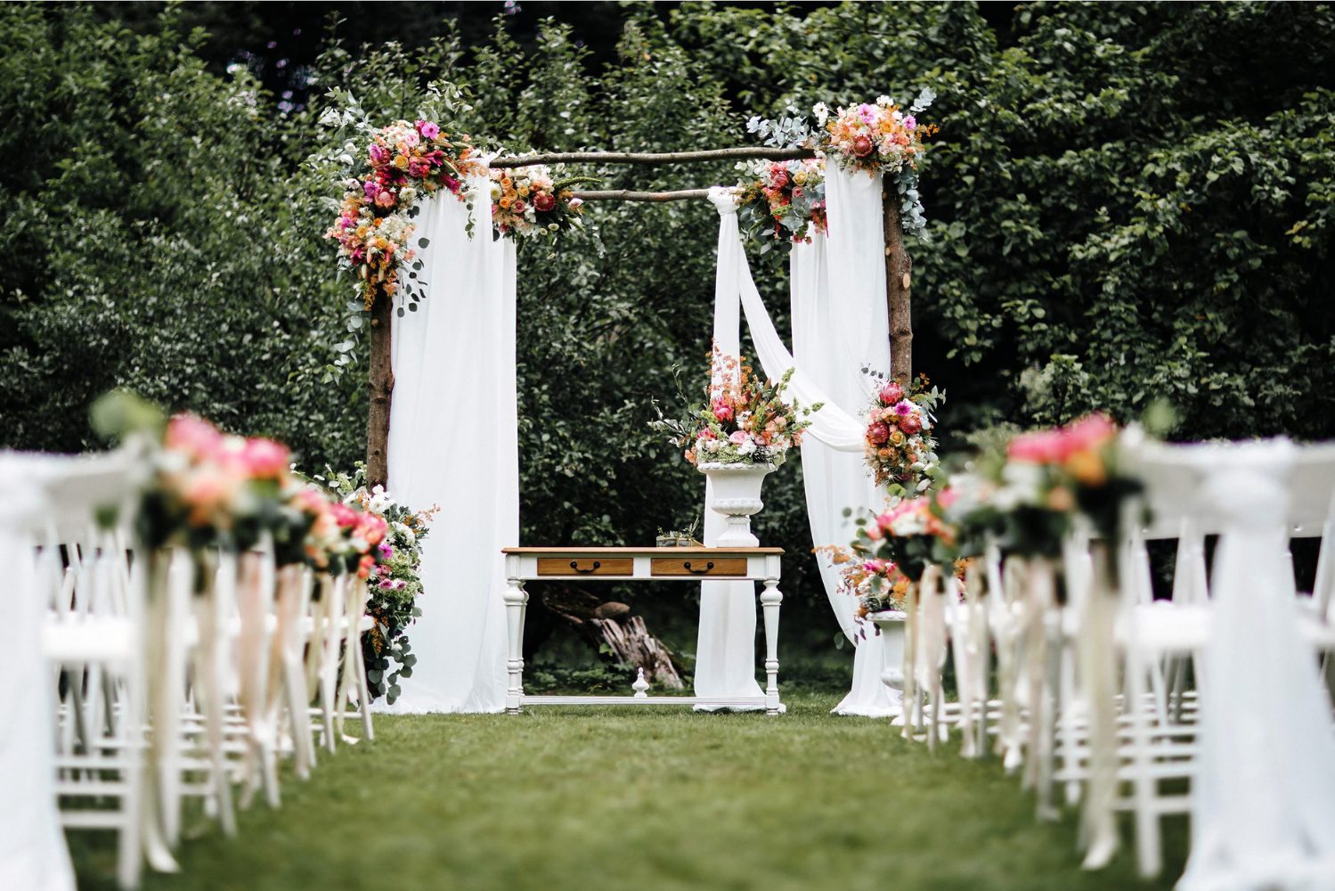 A wedding ceremony with flowers and benches.
