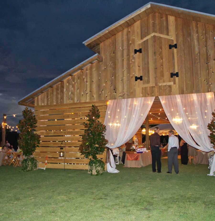 GettyImages-1805941665 A group of people standing outside of a barn.