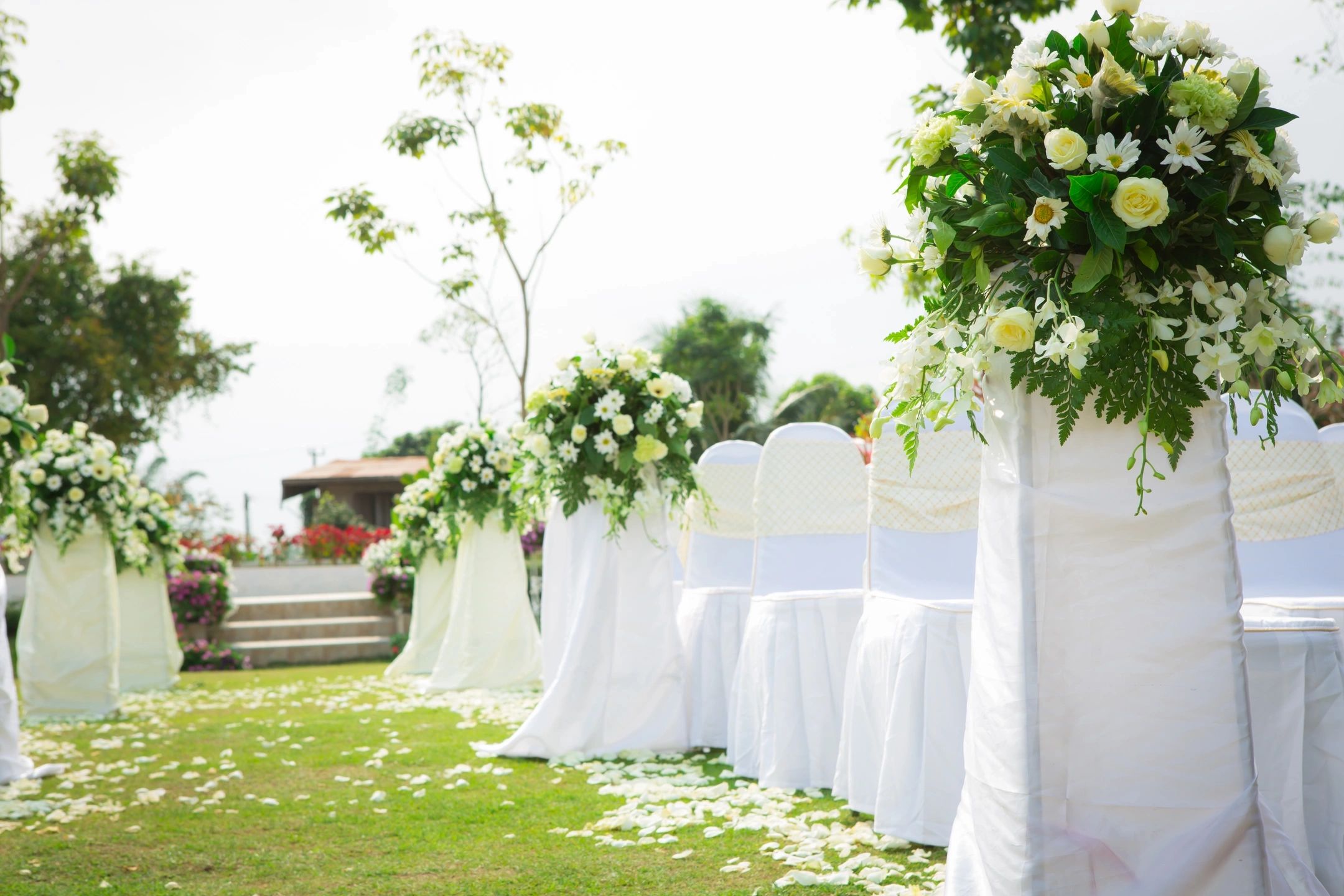 A wedding ceremony with white chairs and flowers.