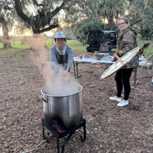 Two people standing next to a large pot.
