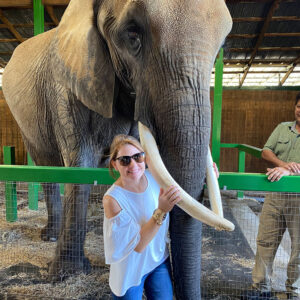 A woman holding the trunk of an elephant.