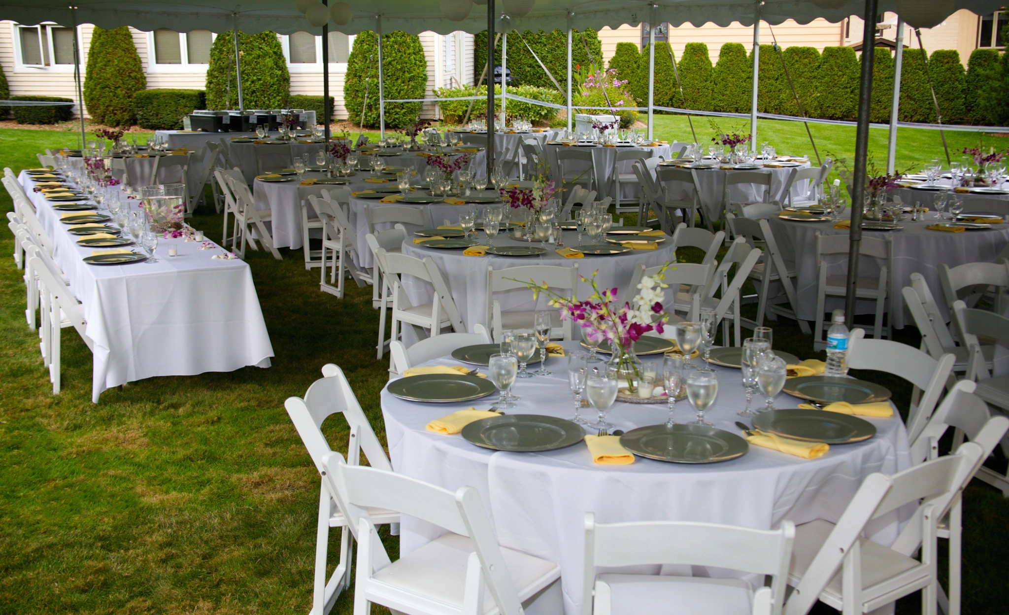 A large white tent with tables and chairs set up for an outdoor event.